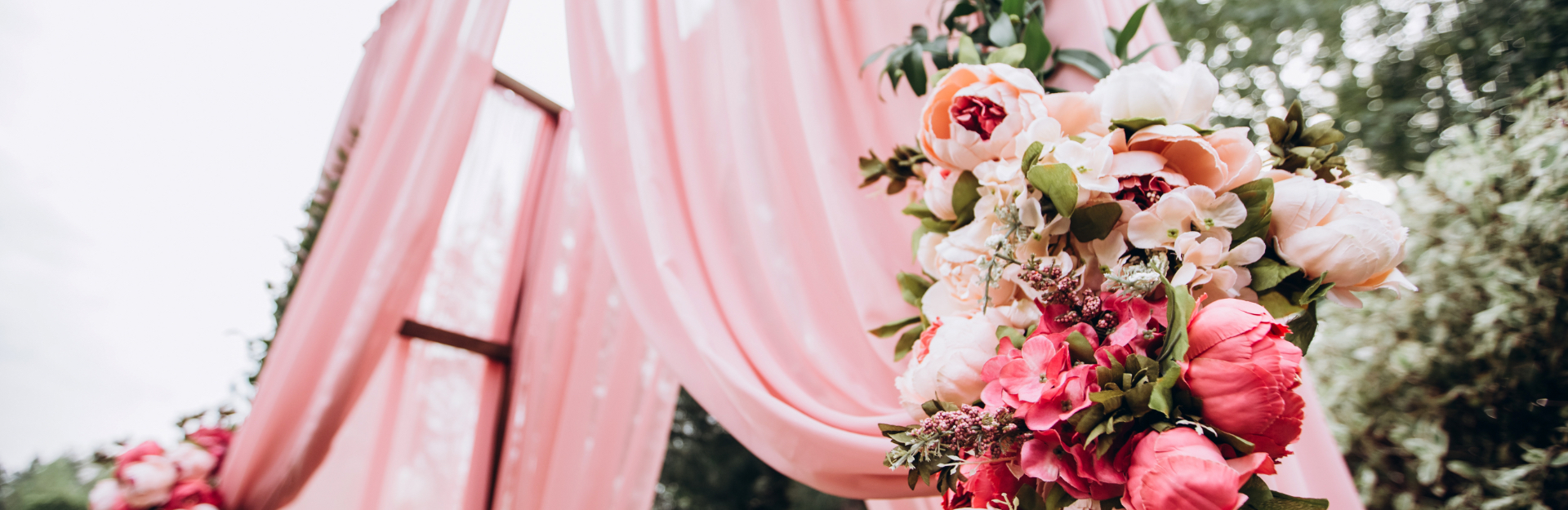 Wedding ceremony arch with pink fabric and rose bouquet